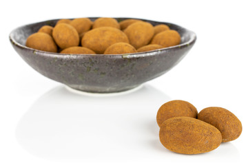 Lot of whole sweet brown chocolate cinnamon almond in dark ceramic bowl isolated on white background