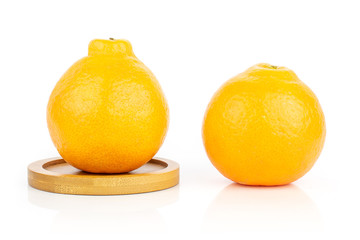 Group of two whole fresh orange tangelo minneola on round bamboo coaster isolated on white background