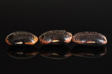 Group of three whole stained purple bean in row isolated on black glass
