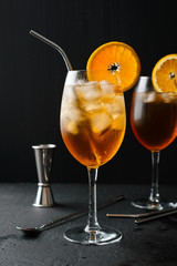 Alcoholic cocktail Aperol Spritz in a wine glass covered with water drops, slice of orange ,ice cubes and metal straw