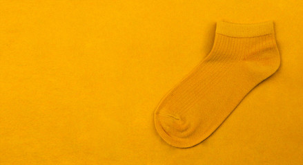 Short sock isolated for your warm message. Cute child orange socks on orange background for winter. Top view. Warm A sock on bright yellow color texture with copy space. Beauty and fashion concept.