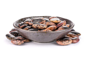 Lot of whole stained purple bean in dark ceramic bowl isolated on white background