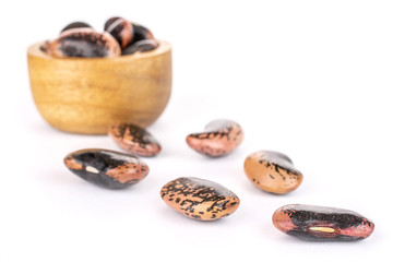 Lot of whole stained purple bean in tiny wooden bowl isolated on white background