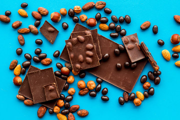 Chocolate bars and nuts on blue table background top view