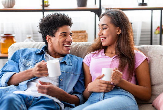 Guy And Girl Drinking Coffee At Home Relaxing On Sofa