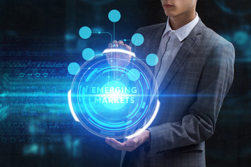 The concept of business, technology, the Internet and the network. A young entrepreneur working on a virtual screen of the future and sees the inscription: Emerging markets