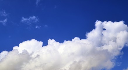 Dramatic and fluffy white clouds on a deep blue summer sky 