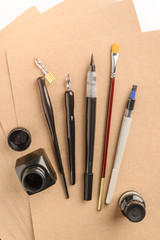 Calligraphy concept, accessories and tools for handwriting,ink, brush,writing training,blank sheets of white paper and cardboard crafting on wooden table
