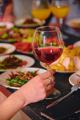 A glass of wine in the hands of a girl on the table.