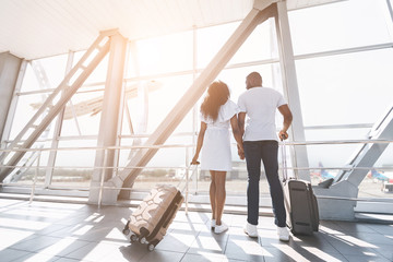 Loving african newlyweds looking at window at airport