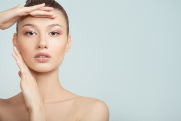 Naklejka premium woman with clean skin touches her cheeks with her hand. face skin concept on a blue background. close-up portrait