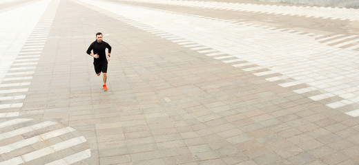 Strong athletic man sprinter running outdoors in city