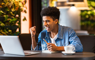 Afro guy expressing success in front of laptop