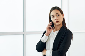 Asian Business woman talking on the phone. Portrait of beautiful girl in office on white background
