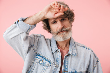 Portrait of disappointed old man with gray beard looking at camera and touching his head