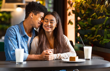 Sweet teen couple holding each other hands in cafe