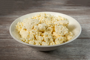 Plate with cottage cheese on a wooden table