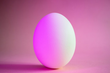 Close-up egg in neon trend pink color. Protein, a stylish simple meal. Minimalism, place for text, design.