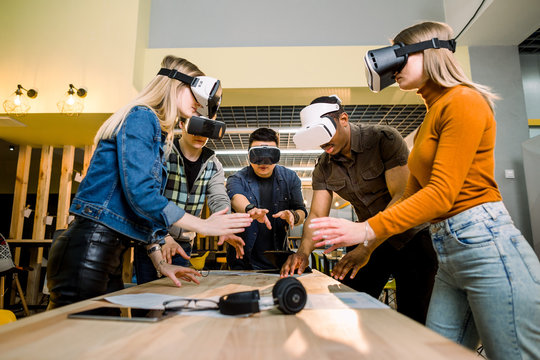 Business people using virtual reality goggles during meeting. Team of multiethnical developers testing virtual reality headset and discussing new ideas to improve the visual experience.