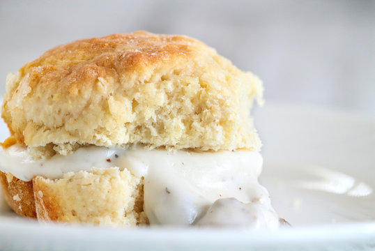 American biscuits from scratch served with thick white sausage gravy. Selective focus against white background.