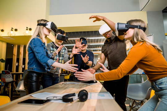 Young multiracial business People wearing virtual reality goggles with touching air during VR Meeting Conference at the office. Business men and women using VR goggles in meeting room.