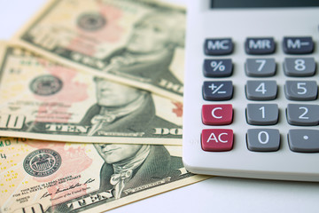 Calculator on ten dollars banknotes on a white background. Concept of Calculation of income and expenses