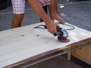 Man working with angle grinder and flap disc as a Sander on wooden shelf