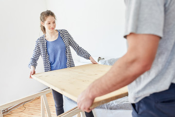 Frau hilft Freund beim Aufbauen von einem Tisch