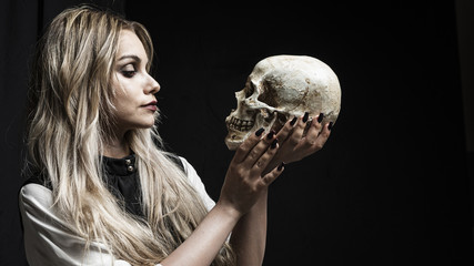 Naklejka premium Woman looking at skull on black background