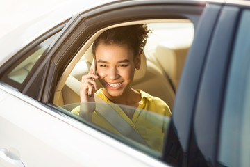 Happy woman sitting in car and talking on phone