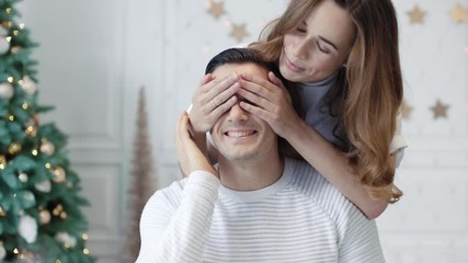 Smiling family celebrating new year in luxury house. Pretty wife presenting gift