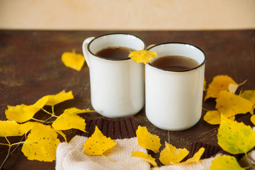 two white cups of tea in the yellow leaves, the concept of cosiness, warmth and autumnal sadness