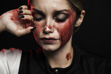 Woman wearing bloody makeup on black background