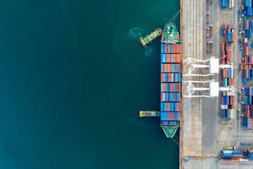 Aerial view and top view. Container ship in pier with crane bridge carries out export  and import business in the open sea. Logistics and transportation. With copy space