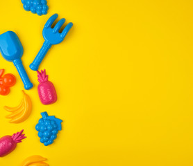 multicolored plastic toys fruits on a yellow  background, copy space