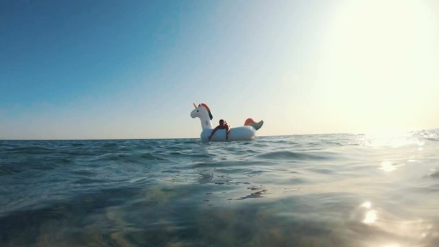 Beautifull girl having fun on inflatable Unicorn. Enjoying summer vacation on a tropical island.