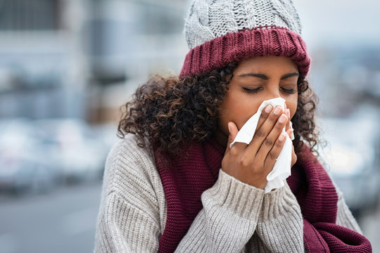 Black woman with cold sneezing outdoor