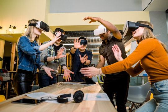 Young multiracial business People wearing virtual reality goggles with touching air during VR Meeting Conference at the office. Business men and women using VR goggles in meeting room.