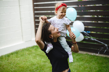 Mother with little girl, playing happy on the green grass.