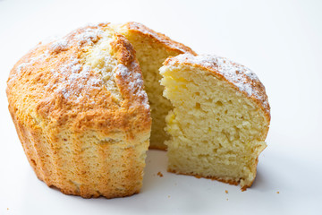 Side view of a freshly baked cupcake with a cut piece on a white background. Bakery products.