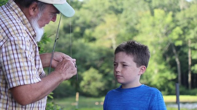 Adult showing child how to put bait on a hook. 