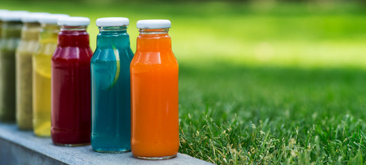 Set of detox cocktails in glass bottles in summer park outdoor
