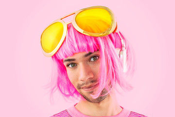 Portrait of a funny young man wearing a pink wig and giant sunglasses