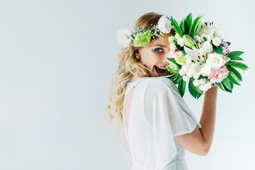 attractive bride in wedding dress and wreath holding bouquet isolated on white