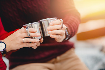 Travelers hold metal mugs with hot coffee tea, autumn mood