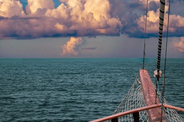 The bow of the ship against the sea horizon with a grid, steel cables and a folded sail. Ancient...