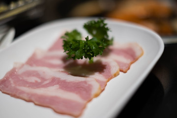 Closeup of bacon slides on from white dish.