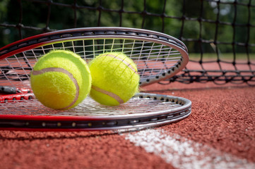 Two tennis balls resting on top of tennis racquet