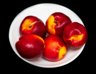 Ripe nectarine in a white plate on a black background