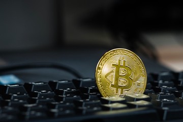 Golden bitcoin token on black computer keyboard